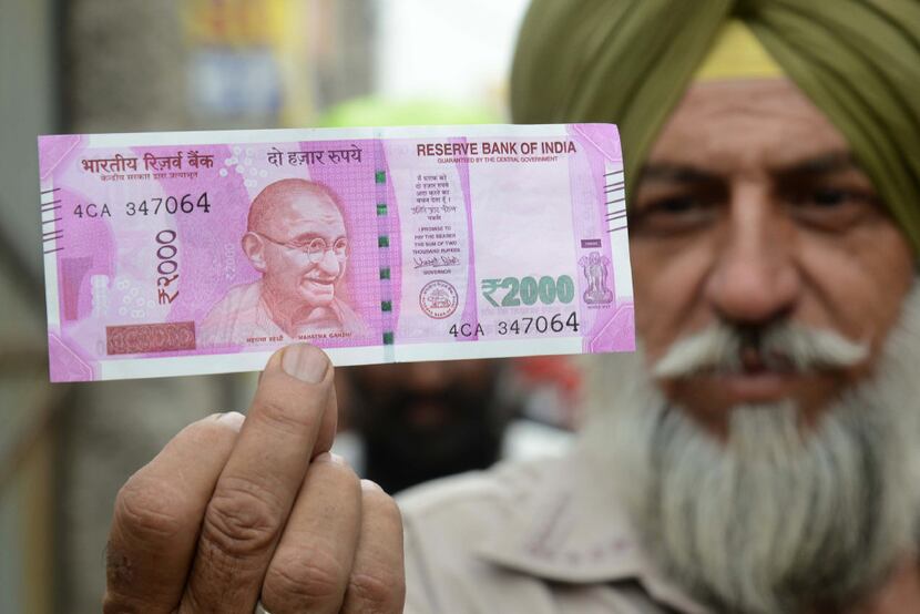 An Indian Sikh man displays a new 2000 rupee note at a bank in Amritsar on November 10,...