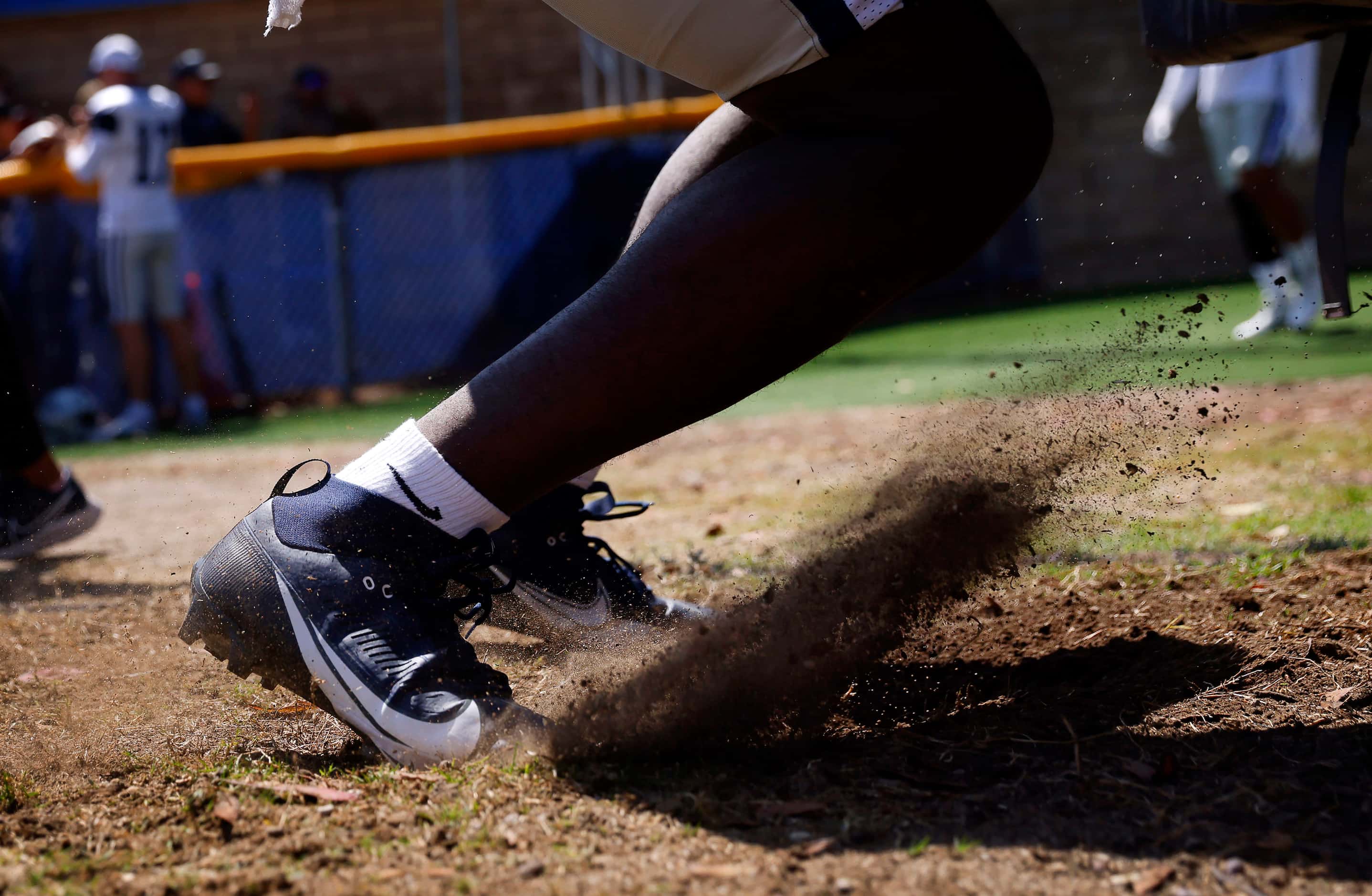 A Dallas Cowboys players kicks the dirt as he lunges into blocking pads before training camp...