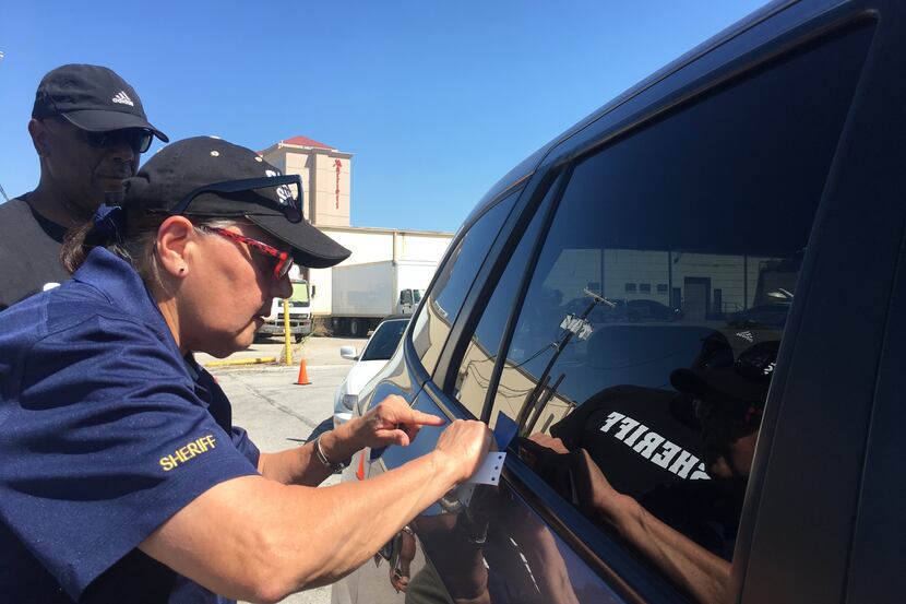 A member of the Dallas County sheriff's office applies a VIN etching stencil to a car...