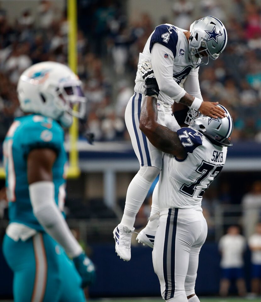 Dak Prescott (4) de los Dallas Cowboys es levantado por el tacle ofensivo Tyron Smith (77)...