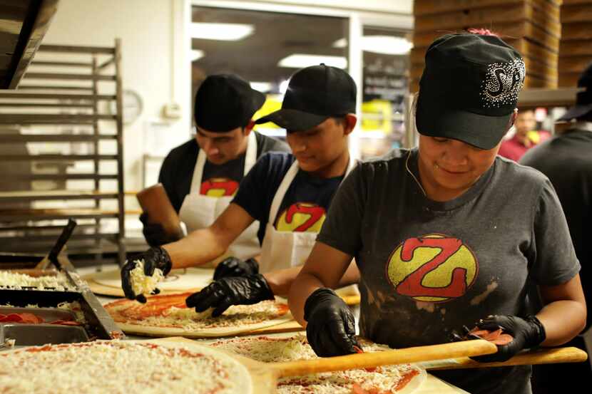 Employees prepare a steady flow of pizzas during a 2 a.m. rush at Zalat Pizza on Fitzhugh...