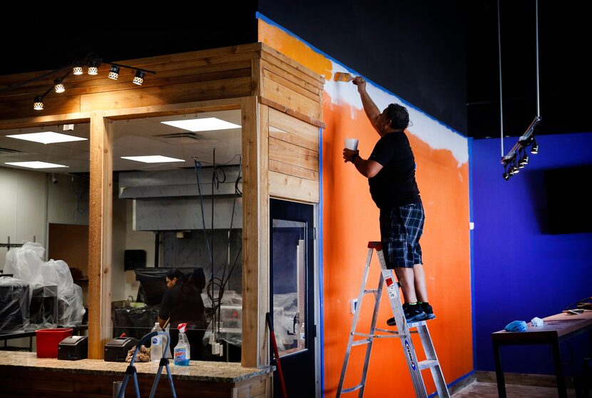 Employee Temo Avila paints one of the colorful walls lining El Rincon del D.F., a tortería...