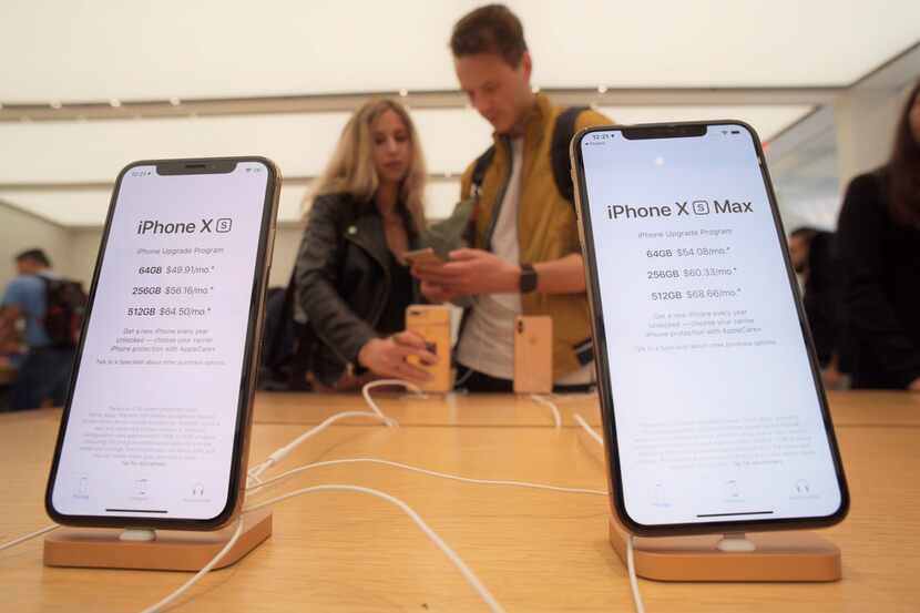 Customers look at new Apple iPhones, including the iPhone XS, left, iPhone XS Max on display...