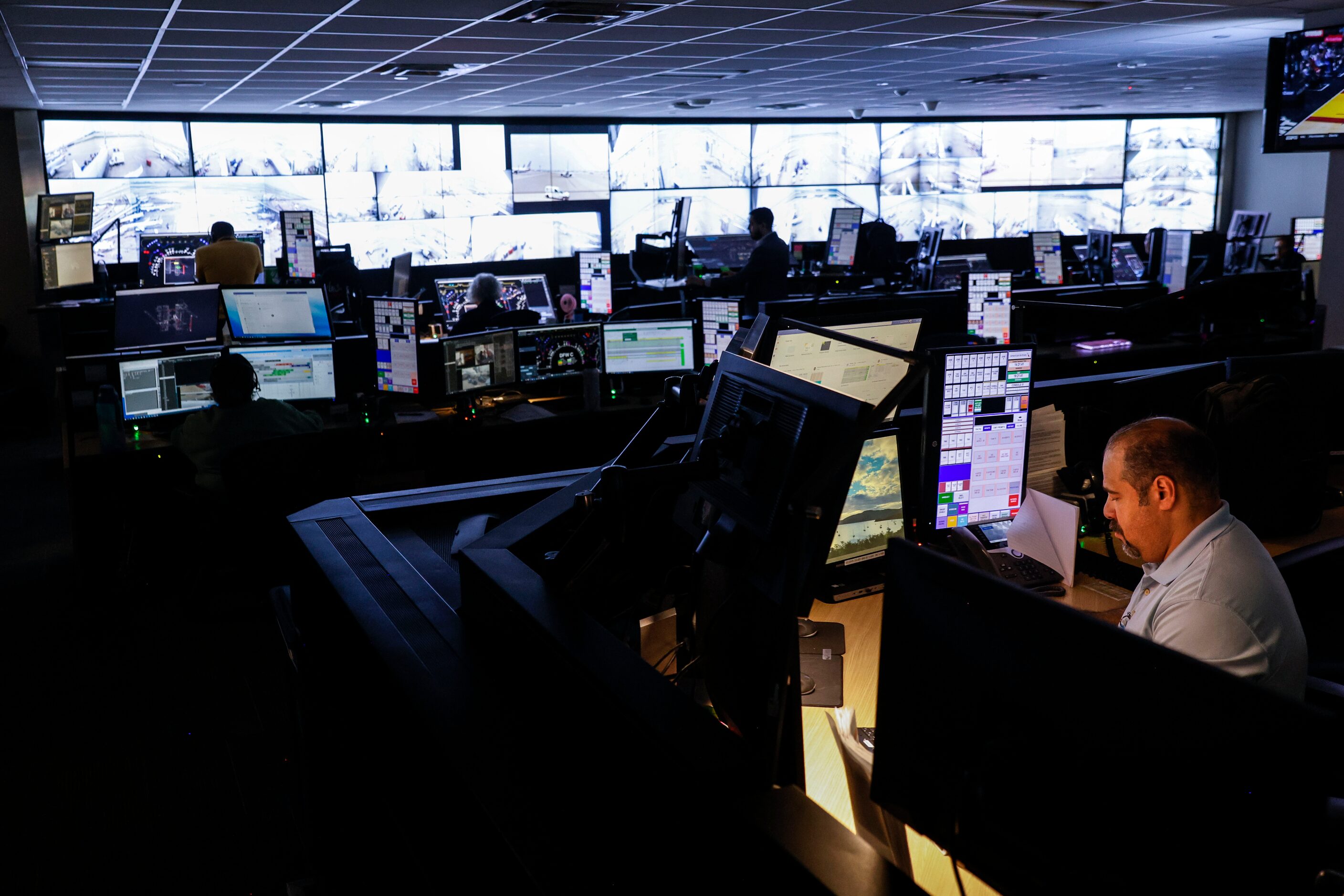 Employees work at American Airlines control hub, where the airline directs its ground...