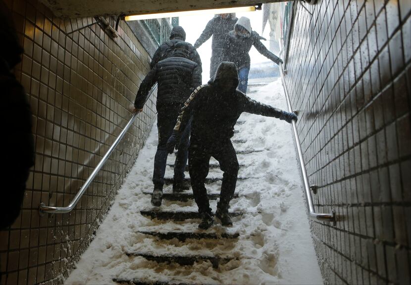  Travelers navigate snow covered steps at the Union Turnpike subway station in the Queens...