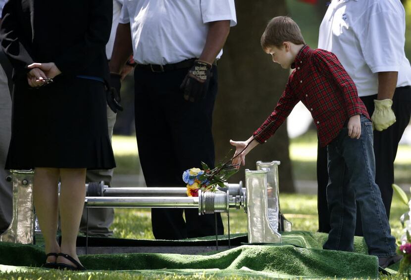 Magnus Ahrens, the 8-year-old son of Dallas Officer Lorne Ahrens, drops flowers into his...