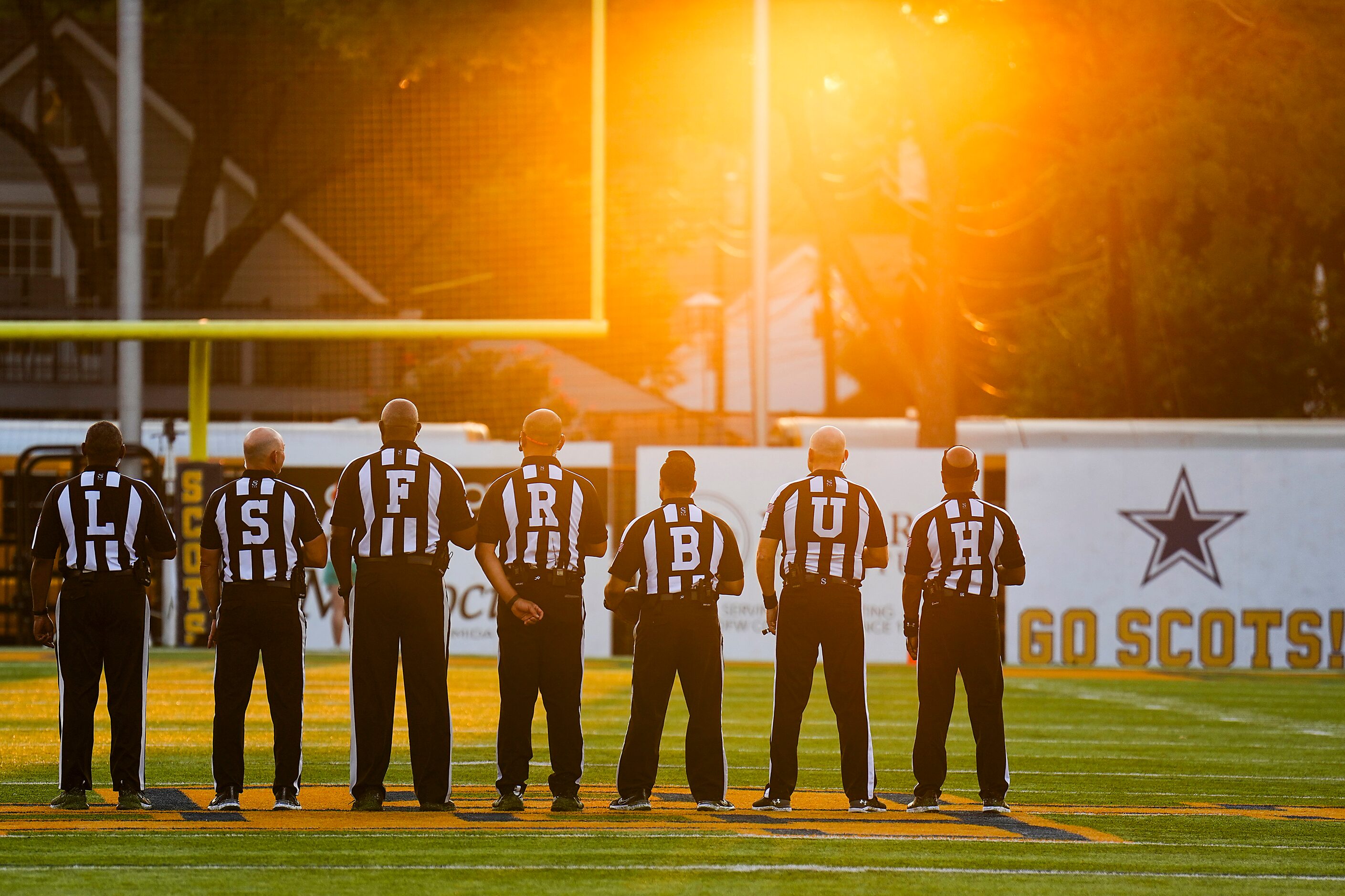 Officials stand for the national anthem before a high school football game Highland Park and...