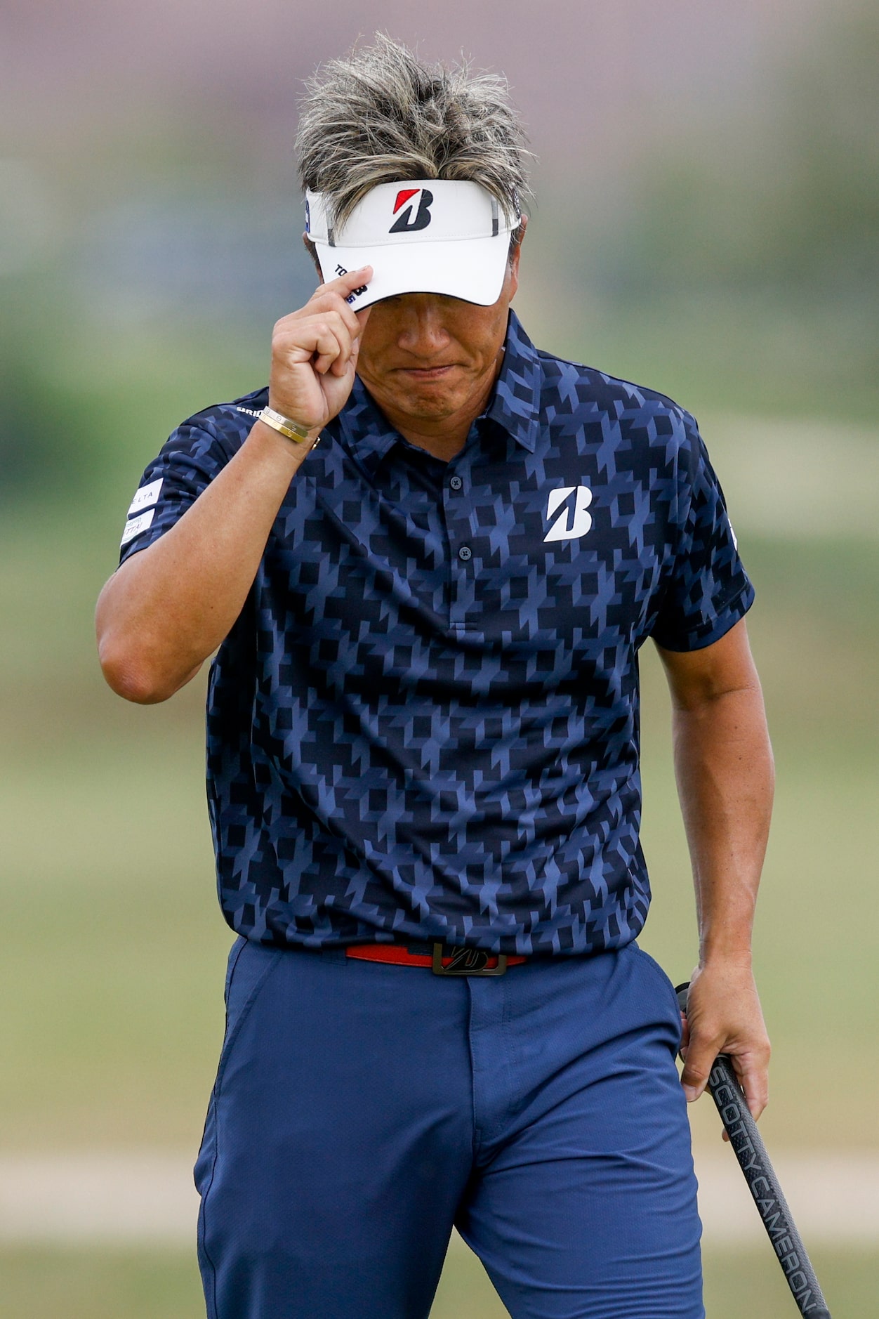 Katsumasa Miyamoto of Japan tips his visor to fans after sinking a birdie putt on the...