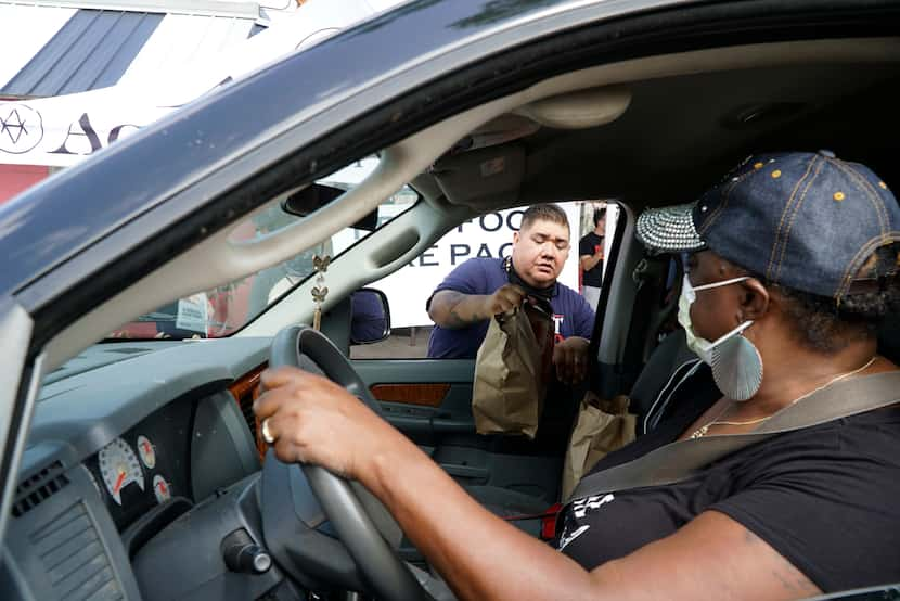 Chef Kevin Martinez loads bags of meals to Sharon Russell during a food giveaway in the Near...