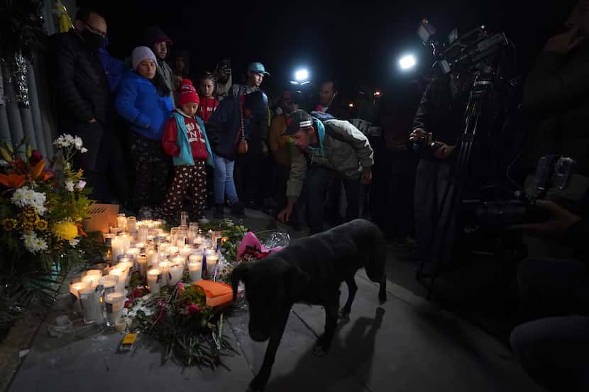 A migrant lights a candle during a vigil for the victims of a fire at an immigration...