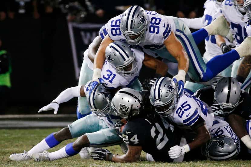 Oakland Raiders running back Marshawn Lynch (24) is tackled by the Dallas Cowboys defense in...