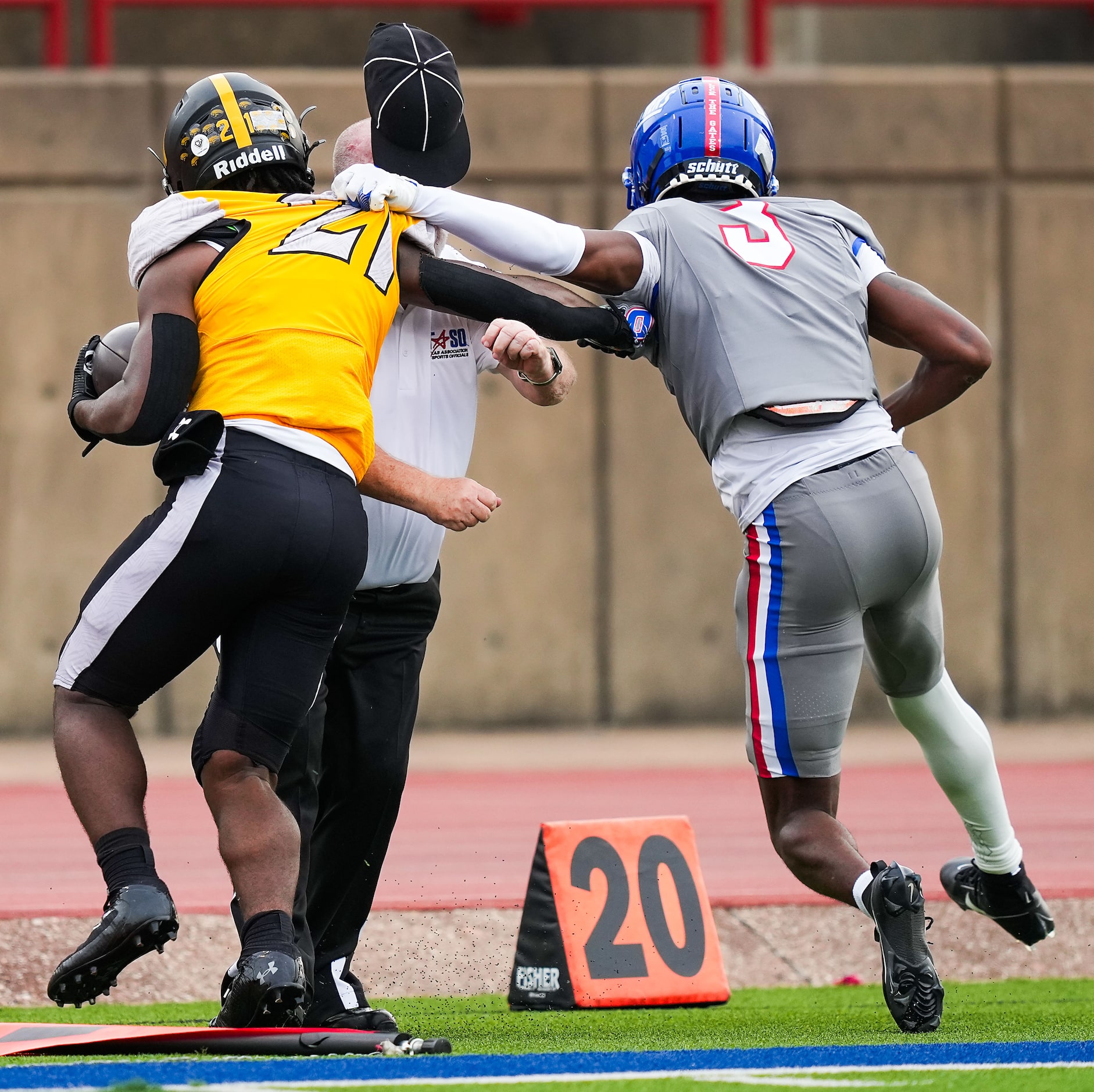 A sideline official is knocked down as Duncanville defensive back Javion Holiday (3) drives...