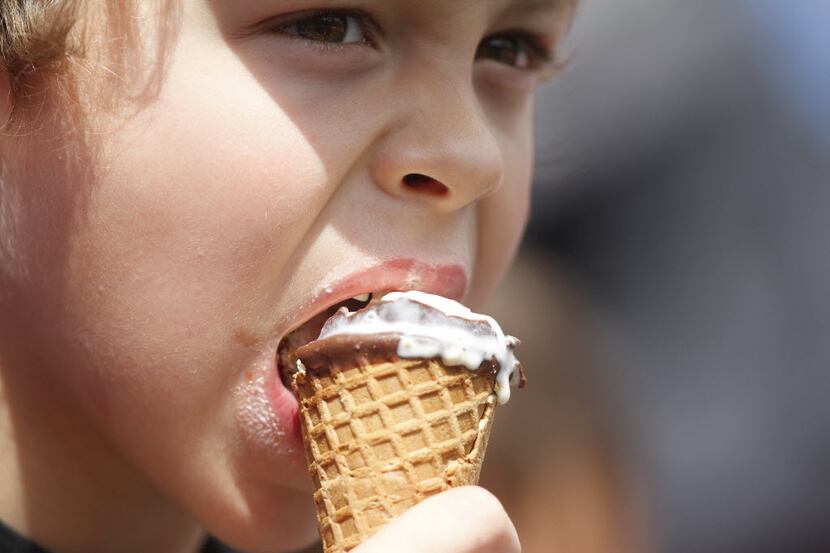After a morning of rain, a kid eats an ice cream cone while watching the Rangers play the...