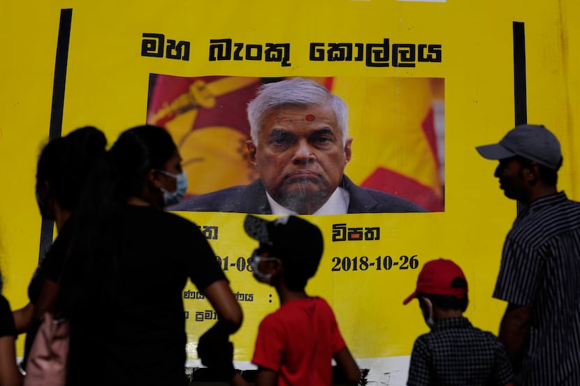 People watch propaganda materials displayed against prime minister Ranil Wickremesinghe...