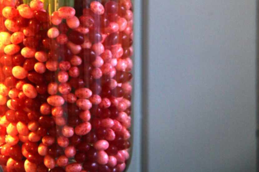 Jelly beans fill in the dry gap between a smaller cylindrical vase fit inside a larger vase...