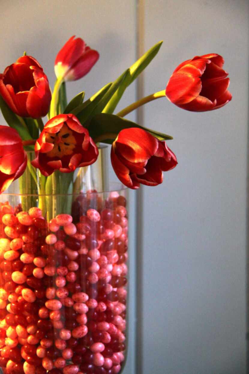 Jelly beans fill in the dry gap between a smaller cylindrical vase fit inside a larger vase...