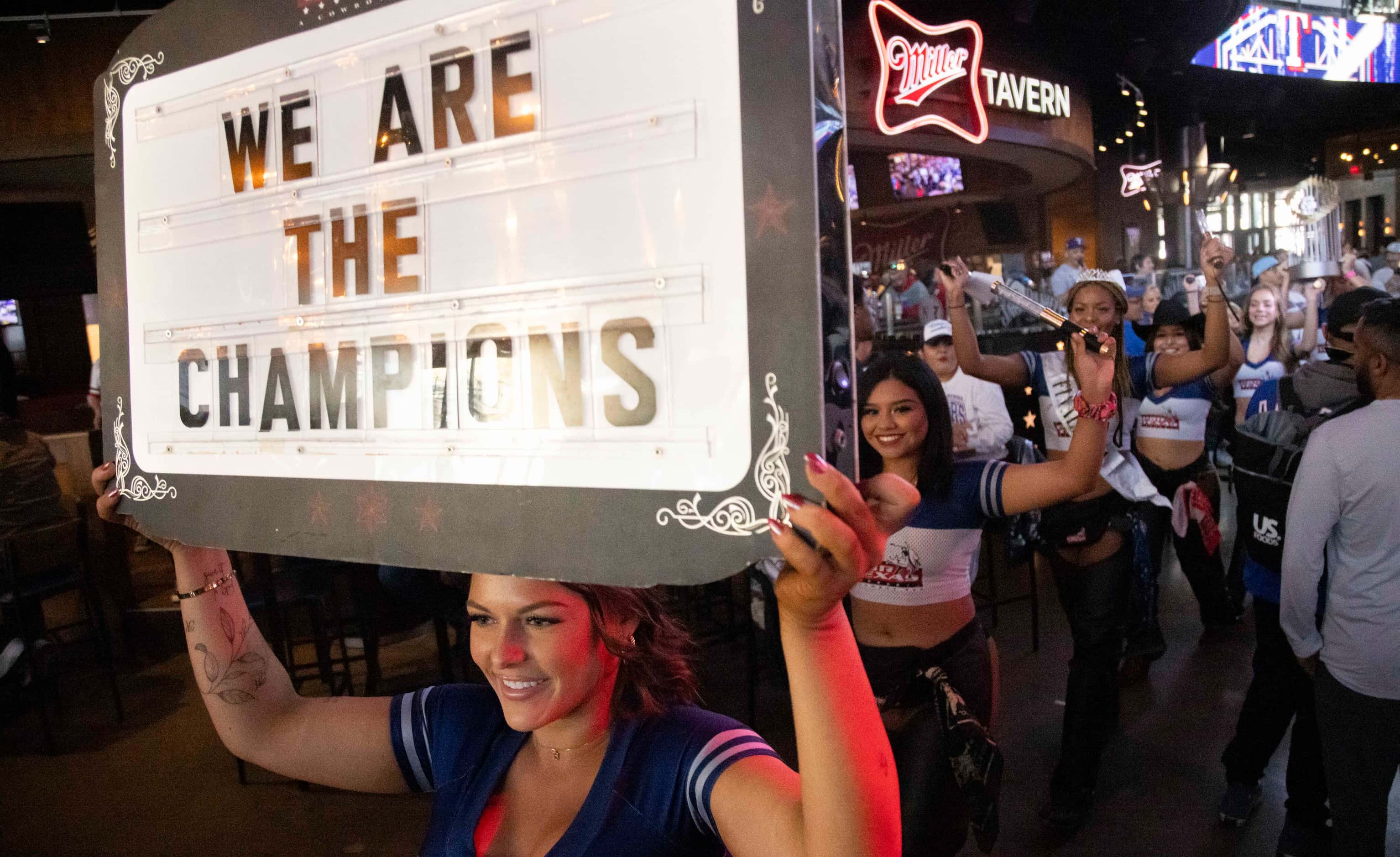 Bottle service features a sign that says “We are the champions” followed by a replica...