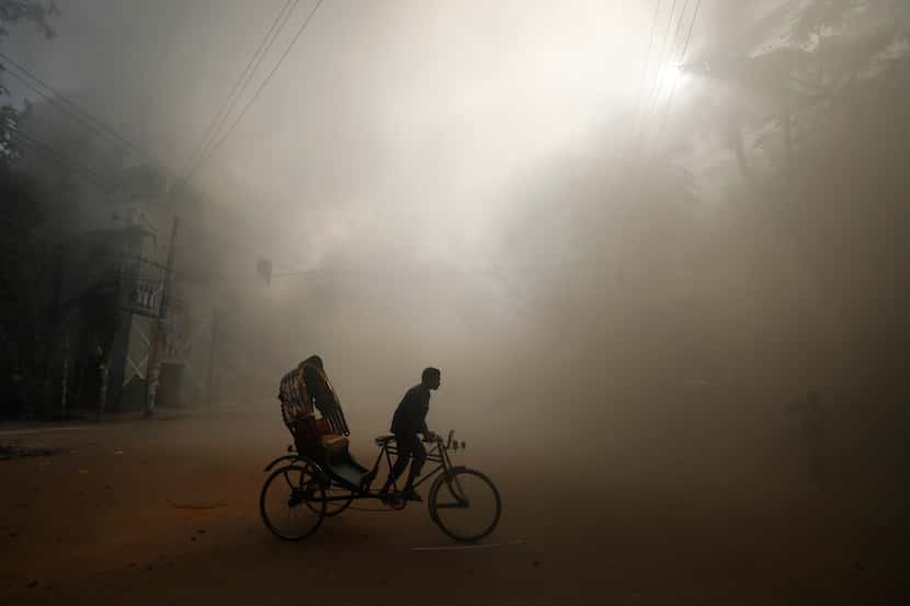 In Dhaka, Bangladesh, on Sunday, Aug. 4, 2024, a rickshaw puller rode in the smoke caused by...