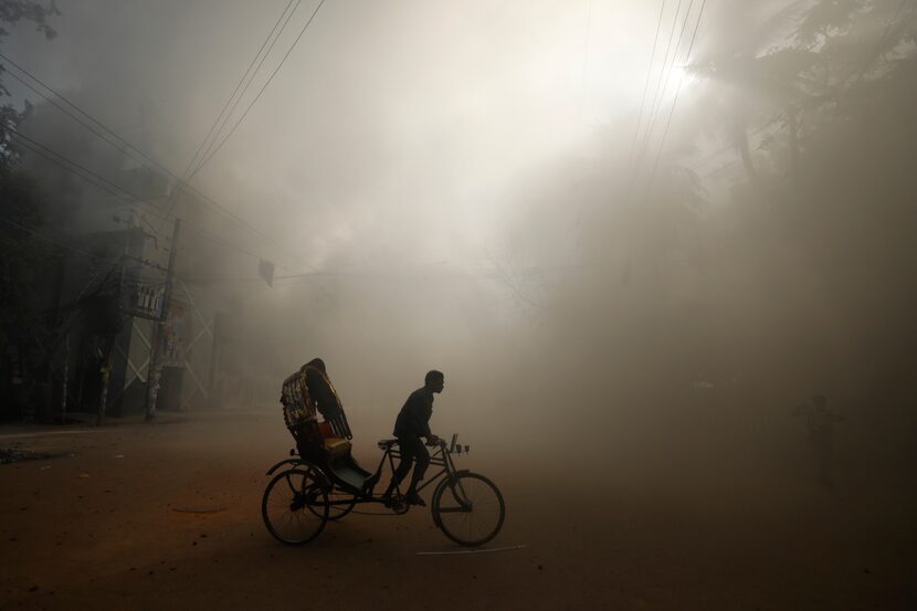 In Dhaka, Bangladesh, on Sunday, Aug. 4, 2024, a rickshaw puller rode in the smoke caused by...