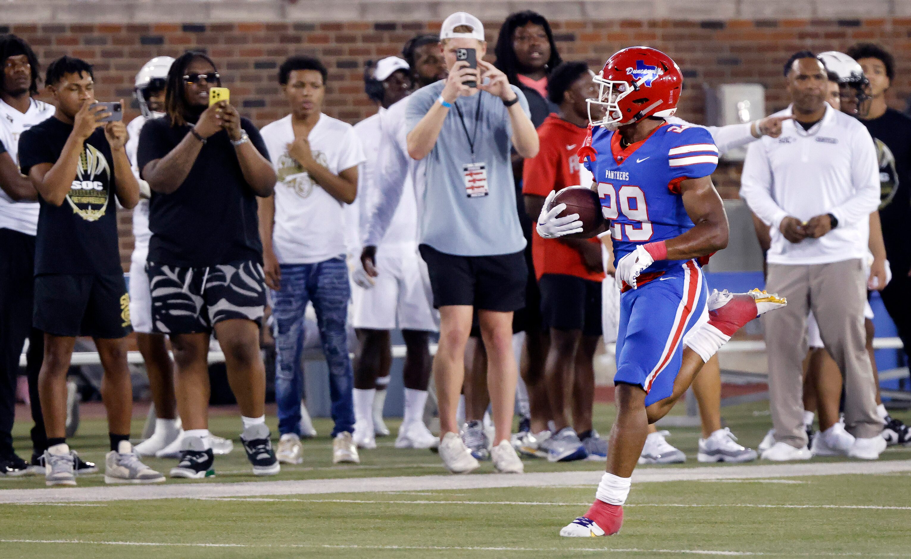 People on the sideline photograph Duncanville running back Caden Durham (29) who carried the...