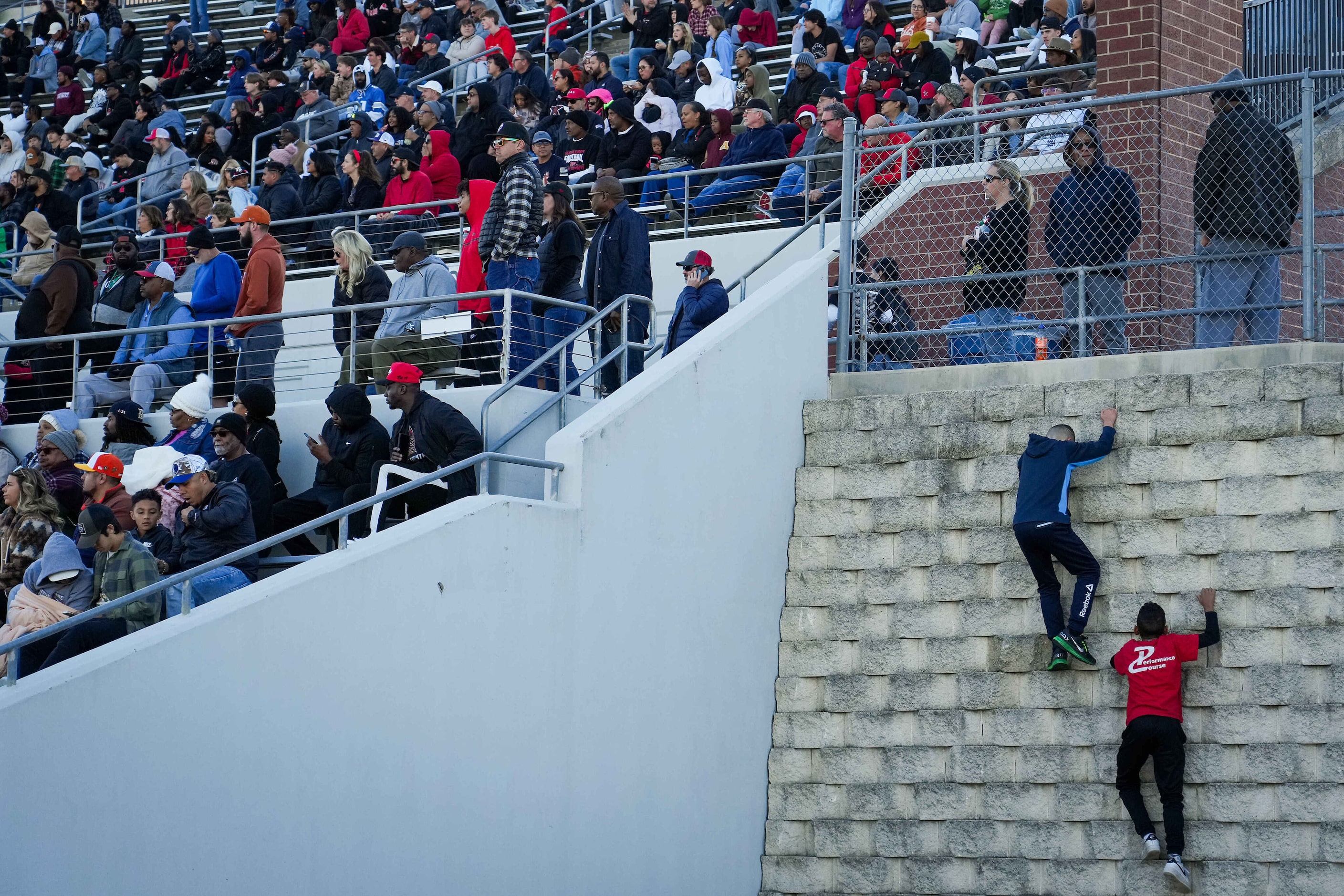 Youngsters try to climb a retaining wall during the second half of a UIL Class 6A Division I...