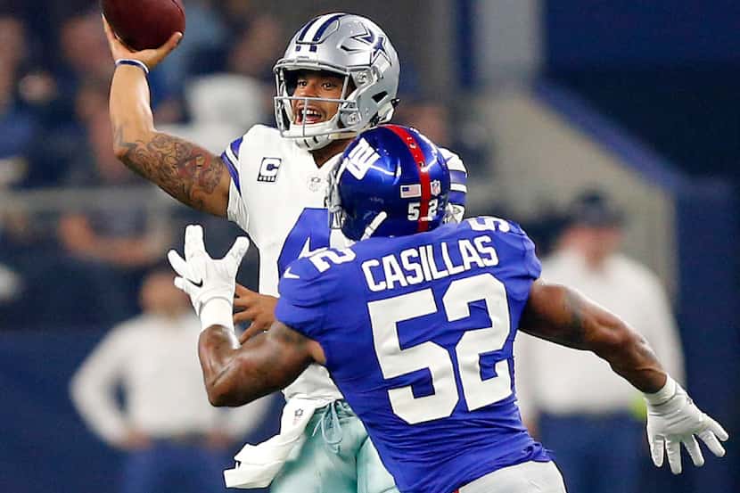 Dallas Cowboys quarterback Dak Prescott (4) rolls out and throws a pass while being pursued...