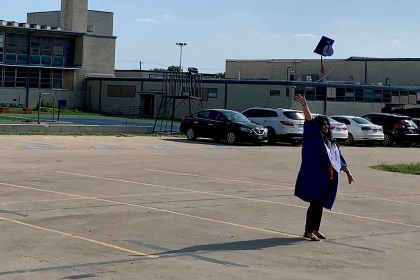 A young woman throws her cap into the air after a socially distanced graduation celebration...