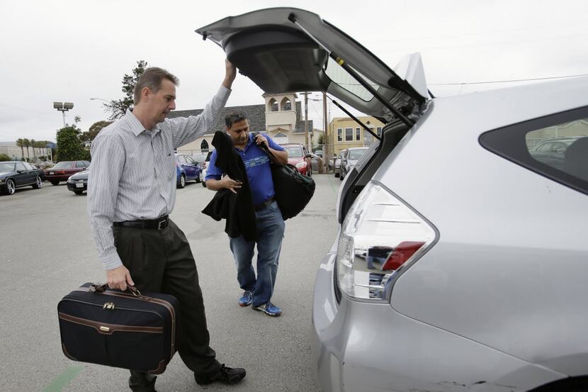 John Penny, left, and Marty Puranik load their luggage into a rental Prius in Millbrae,...