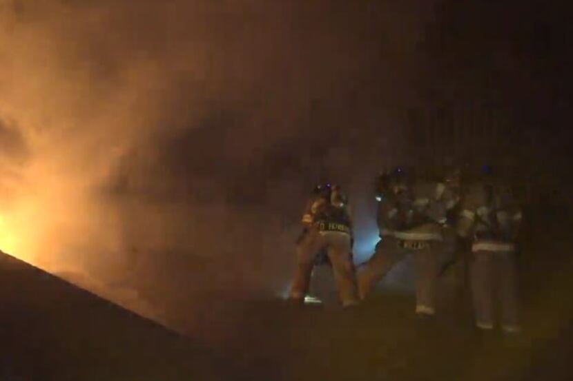 Fort Worth firefighters battle heavy smoke and flames as they try to chop through the roof...