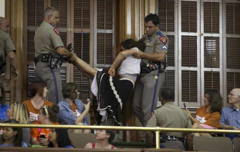 State troopers escorted a demonstrator out of the Senate gallery during Friday's debate.