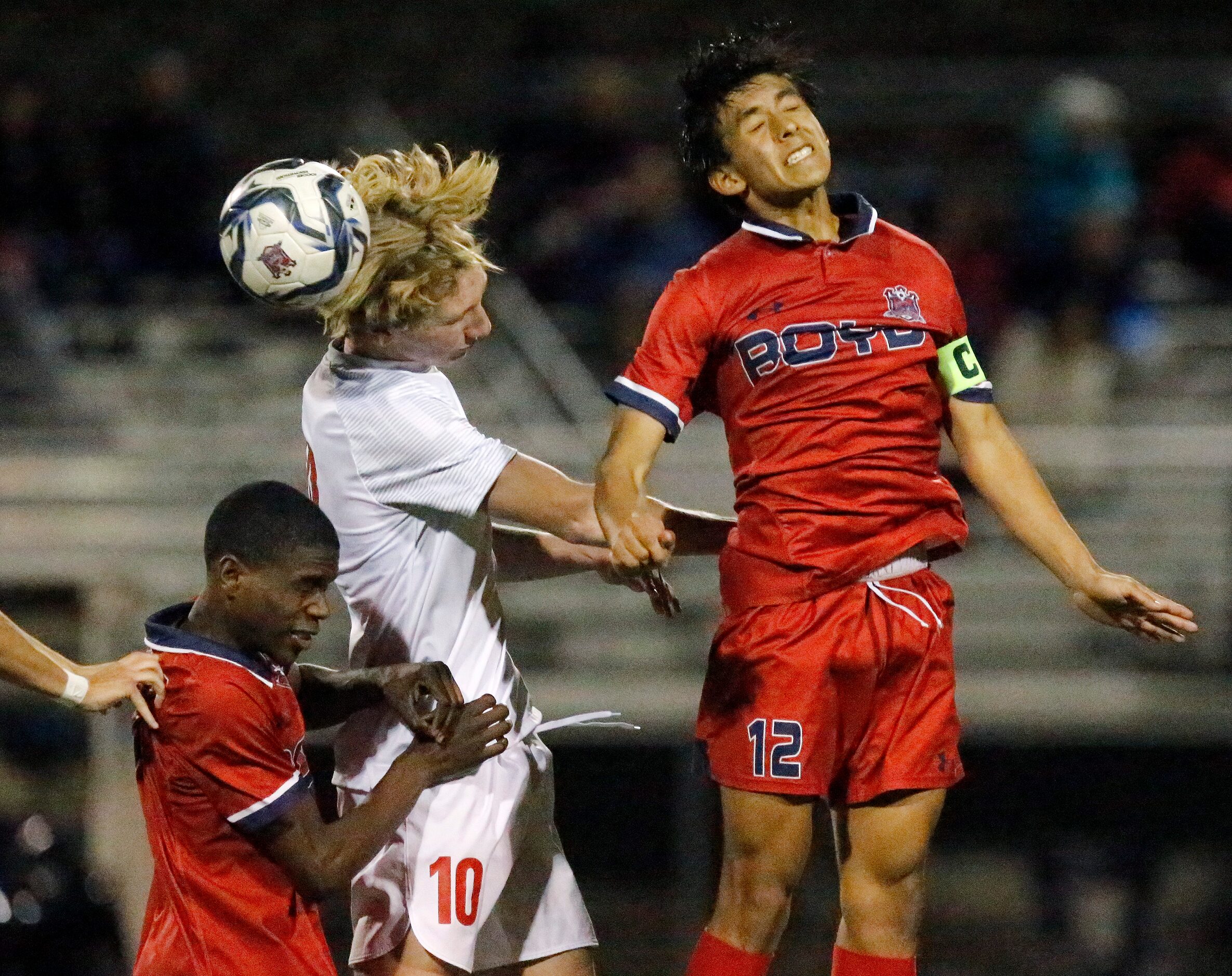 Allen High School midfielder Evan Pustejovsky (10) attempts a header between McKinney Boyd...