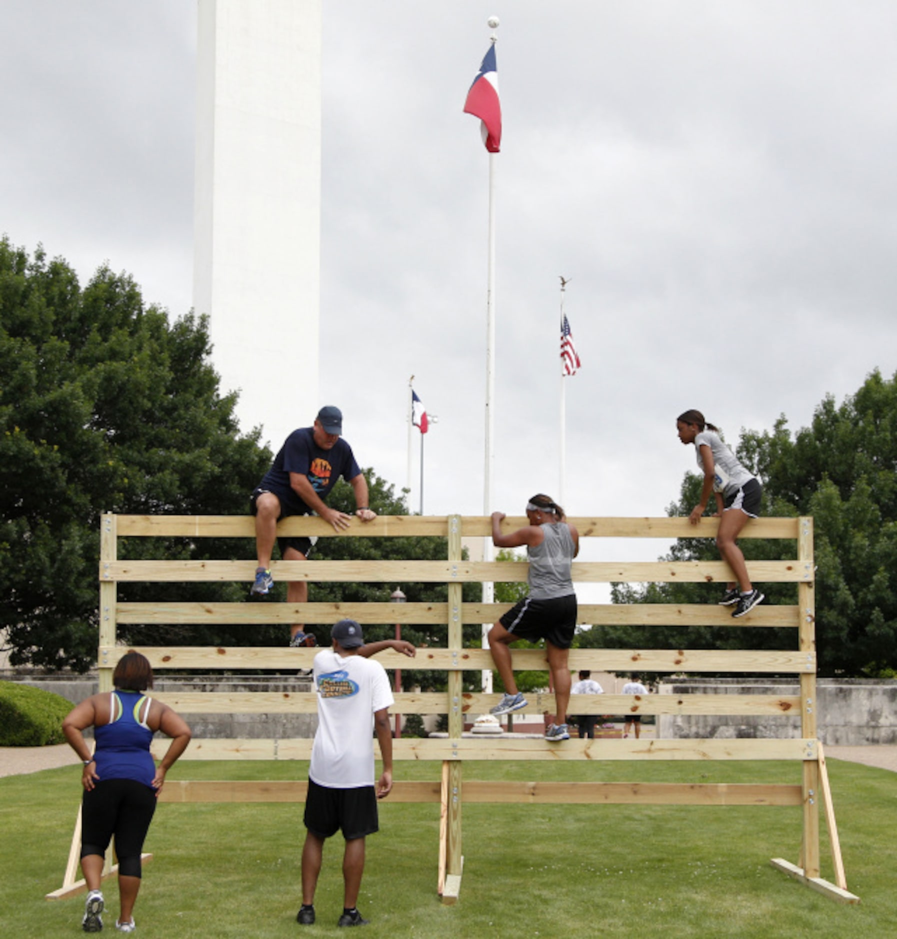 Runners climb over an obstacle during the Second Annual Fair Park 5K Urban Dash Saturday...