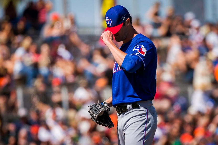 Texas Rangers pitcher Cole Hamels adjusts his cap after giving up a home run to San...