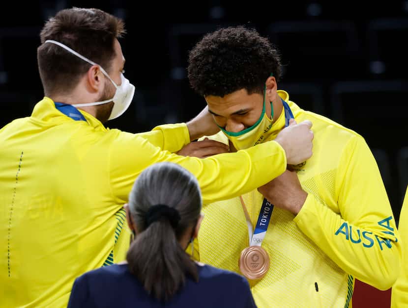 Australia’s Matthew Dellavedova (8) places a bronze medal on Josh Green (6, right) during...
