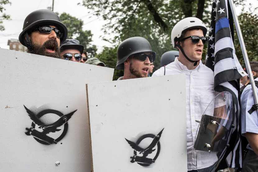 White supremacists with signs emblazoned with the Fasces, an ancient Roman ax and symbol of...
