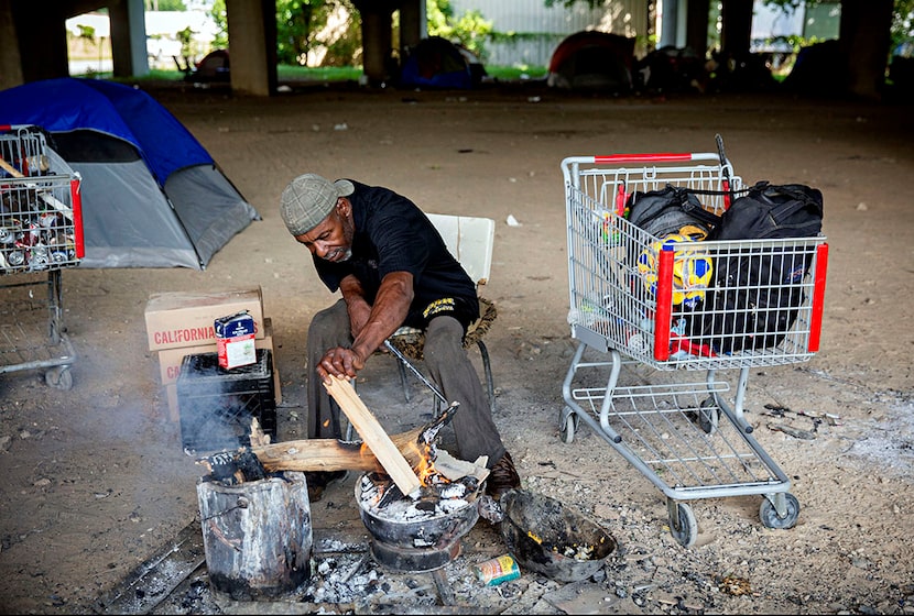  Glendale Davis adds wood to a fire as he readies a fire for dinner in May 2016 at a...