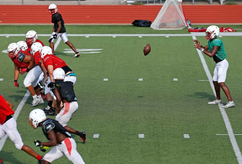 Quarterback Brendon Lewis (right) takes a snap out of the shotgun as he runs the spread...