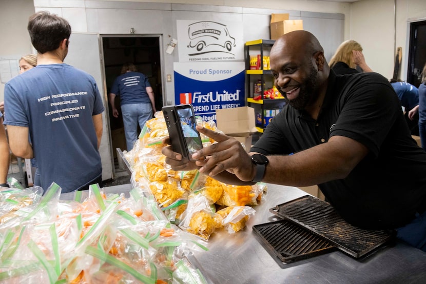 CEO of Hunger Busters Latame Phillips takes photos as volunteers from Accelerate Investment...