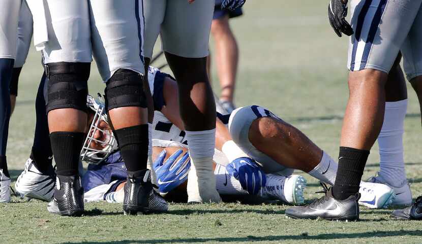 Dallas Cowboys defensive end Tyrone Crawford (98) grimaces as he grabs his right ankle after...