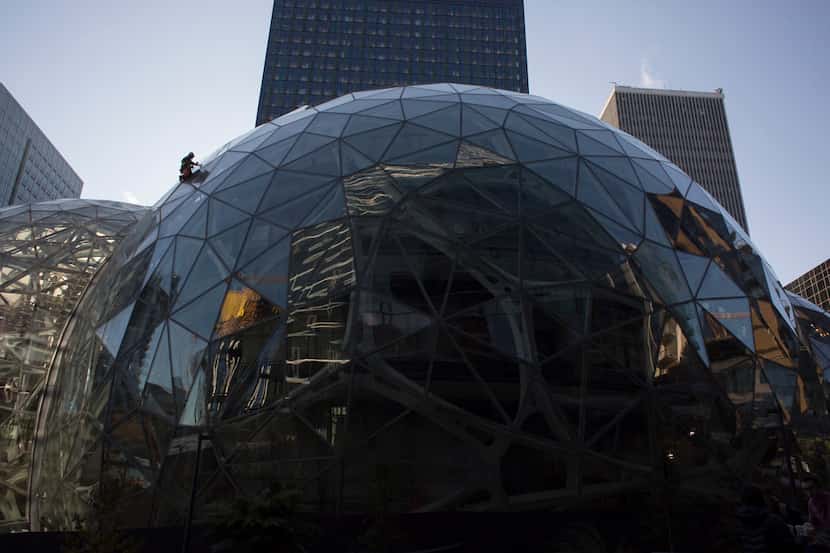 A worker cleans the exterior of one of three glass spheres at Amazon headquarters in...