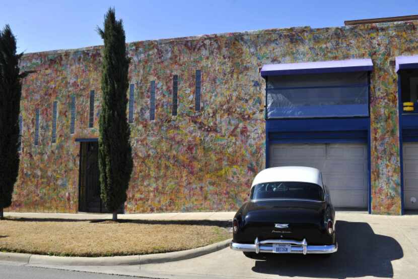A car sits parked outside of a painted house in the Deep Ellum district.