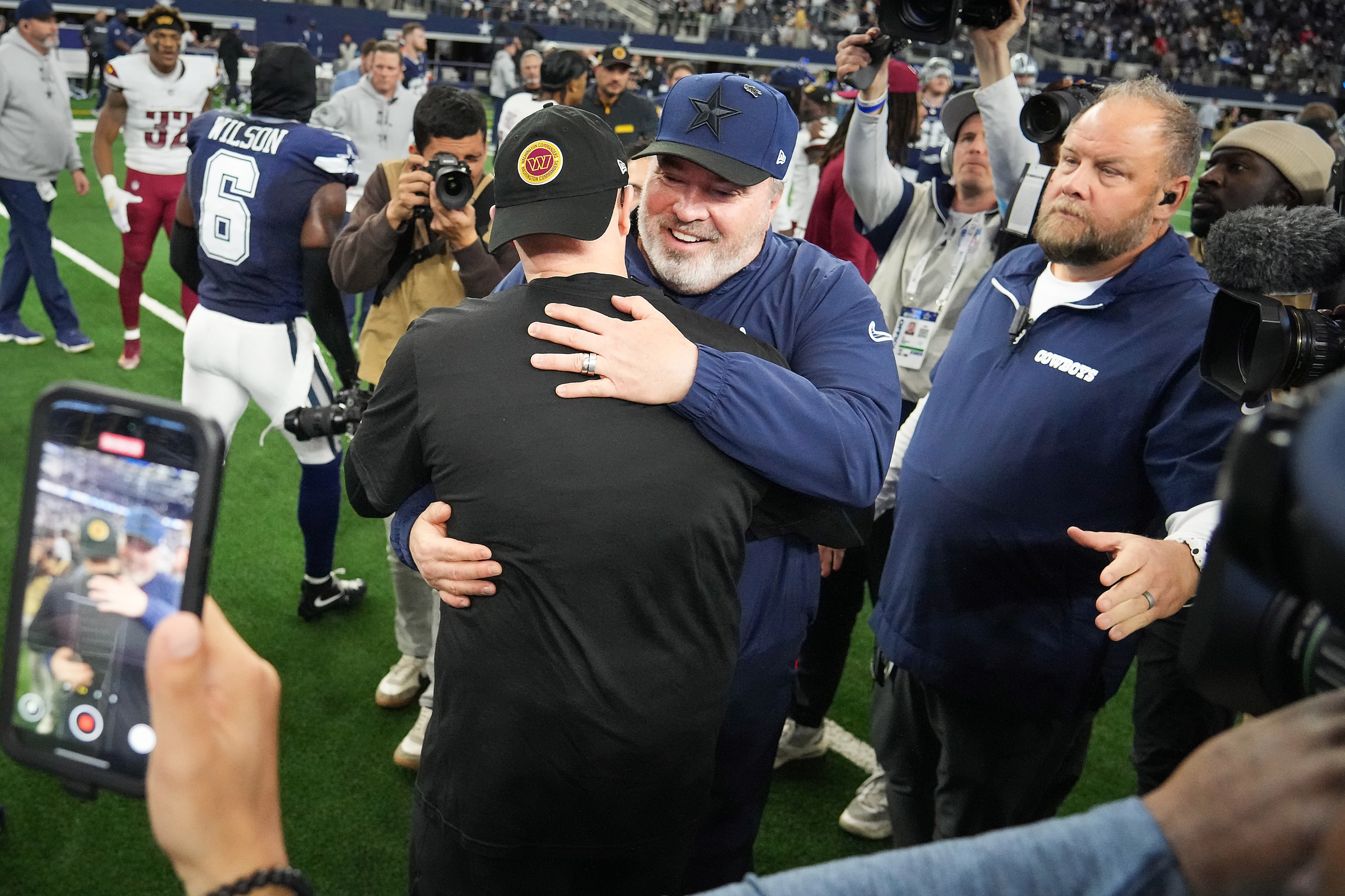 Dallas Cowboys head coach Mike McCarthy (facing) hugs Washington Commanders head coach Dan...