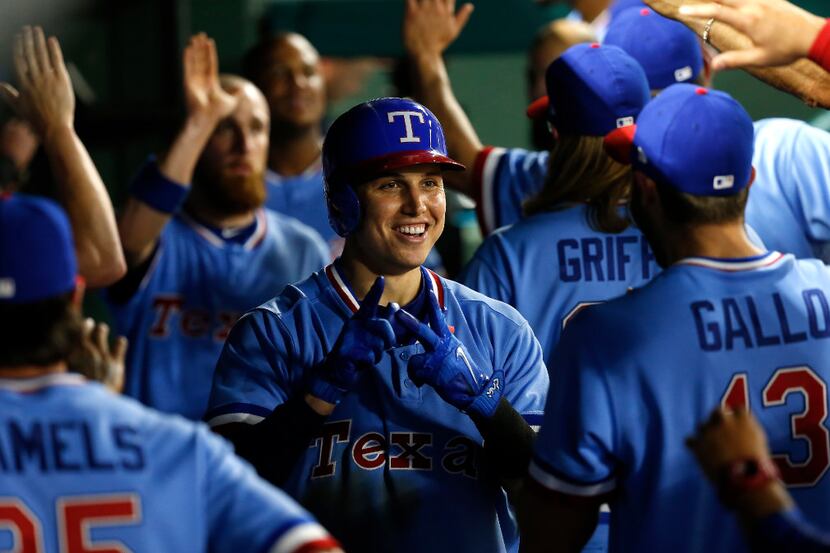 Texas Rangers third baseman Drew Robinson (18) is congratulated by teammates for his two-run...