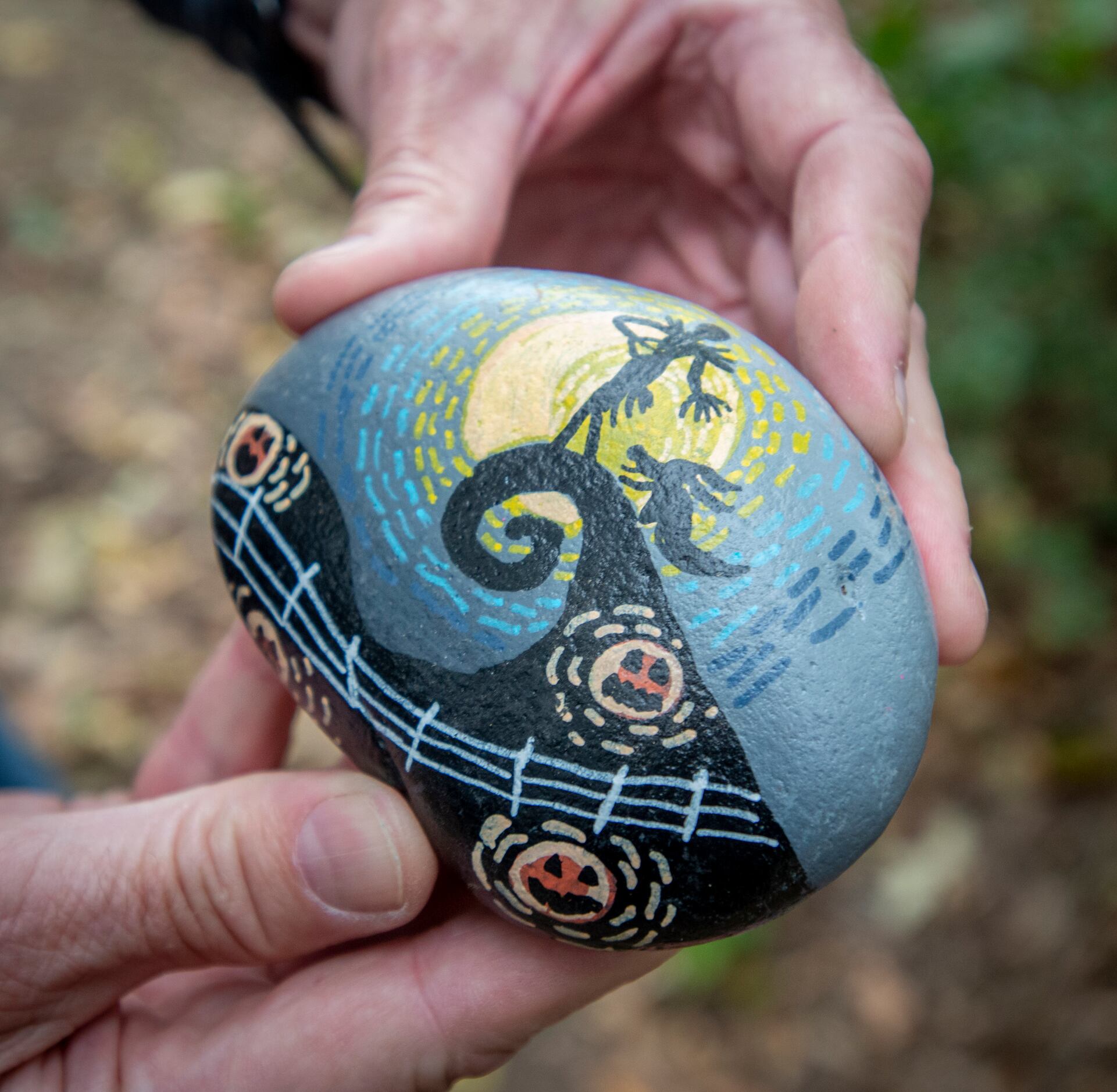 Ron Olsen, who launched the rock art trail, holds one of the hudereds of painted rocks at...