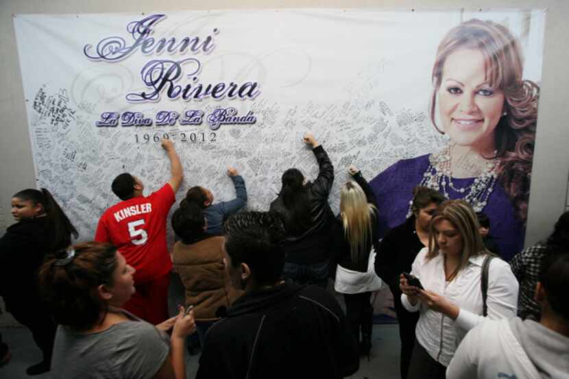 Fans sign a banner writing their thoughts on the late Jenni Rivera before entering a vigil...