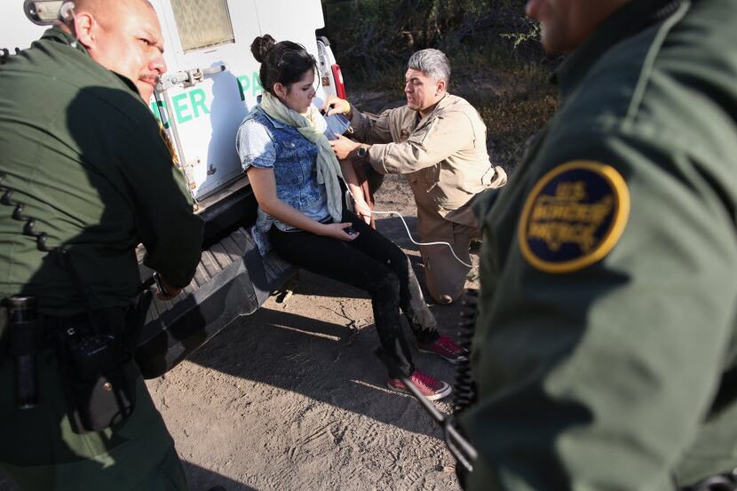 A U.S. Border Patrol agent takes the pulse of an unauthorized immigrant who needed medical...