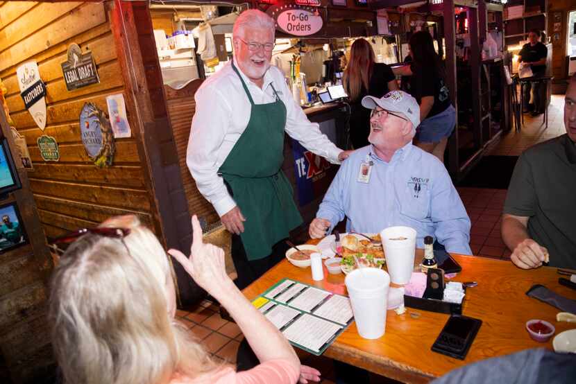 (From center left) Randy Ford, president and owner of J.Gilligan's Bar and Grill, puts a...