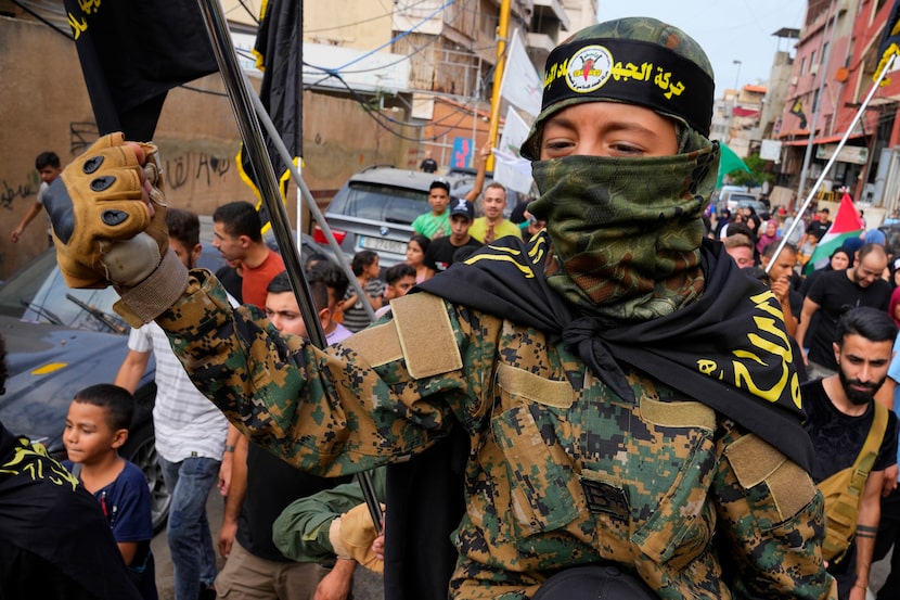 A Palestinian boy wearing army-style fatigues gestures as others dance in celebration of the...