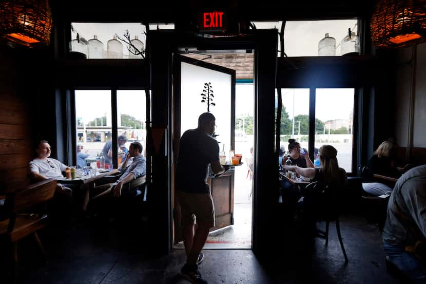 Luciano Gomez delivers a tray full drinks to patrons sitting outside at Las Almas Rotas in...