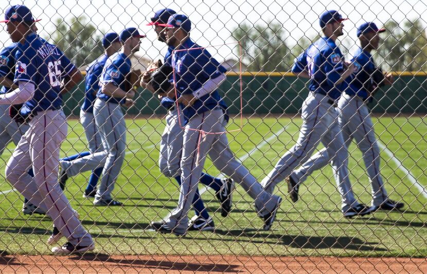 Texas Rangers pitchers head opposite directions as they change stations during a spring...